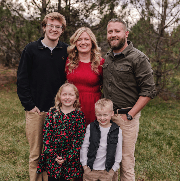 A happy family of five posing outdoors in casual attire.